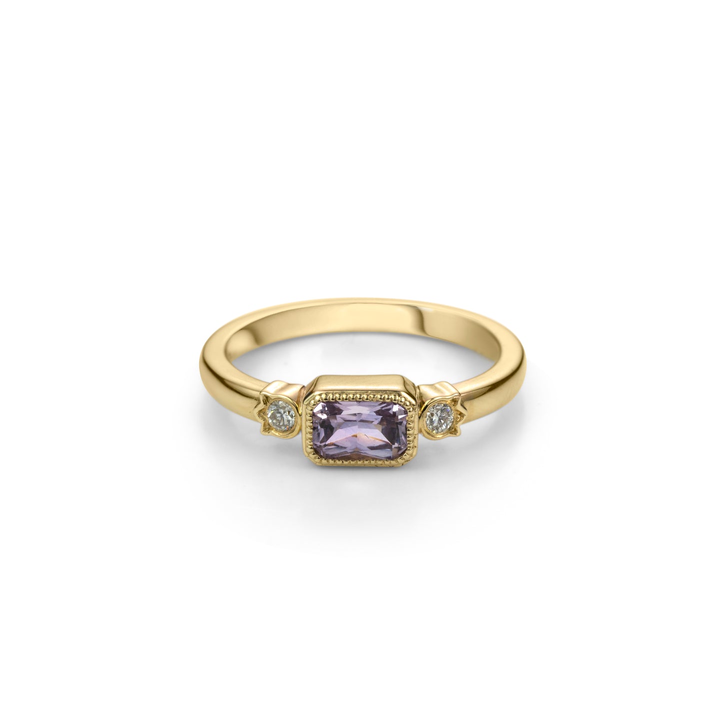 Yellow gold ring with horizontally set radiant cut lilac purple sapphire in millegrained bezel and diamonds in flower shaped setting on each side.