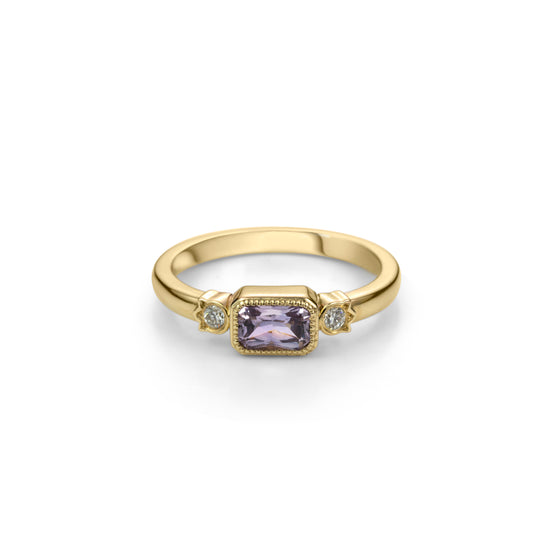 Yellow gold ring with horizontally set radiant cut lilac purple sapphire in millegrained bezel and diamonds in flower shaped setting on each side.