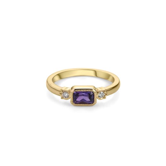 Yellow gold ring with horizontally set radiant cut royal purple sapphire in millegrained bezel and diamonds in flower shaped setting on each side.