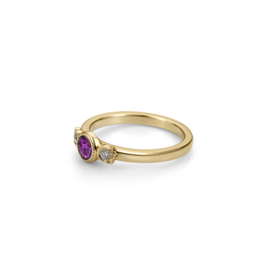 Yellow gold stackable ring with round beaded bezel set plum purple sapphire and diamonds in flower setting on each side in profile view.